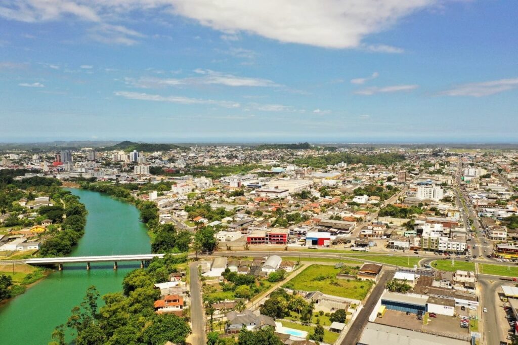 Vista de uma das entradas de Araranguá cidade das avenidas no bairro Cidade Alta, mostrando o rio Araranguá, a ponte, alguns prédios e ao fundo o litoral. 